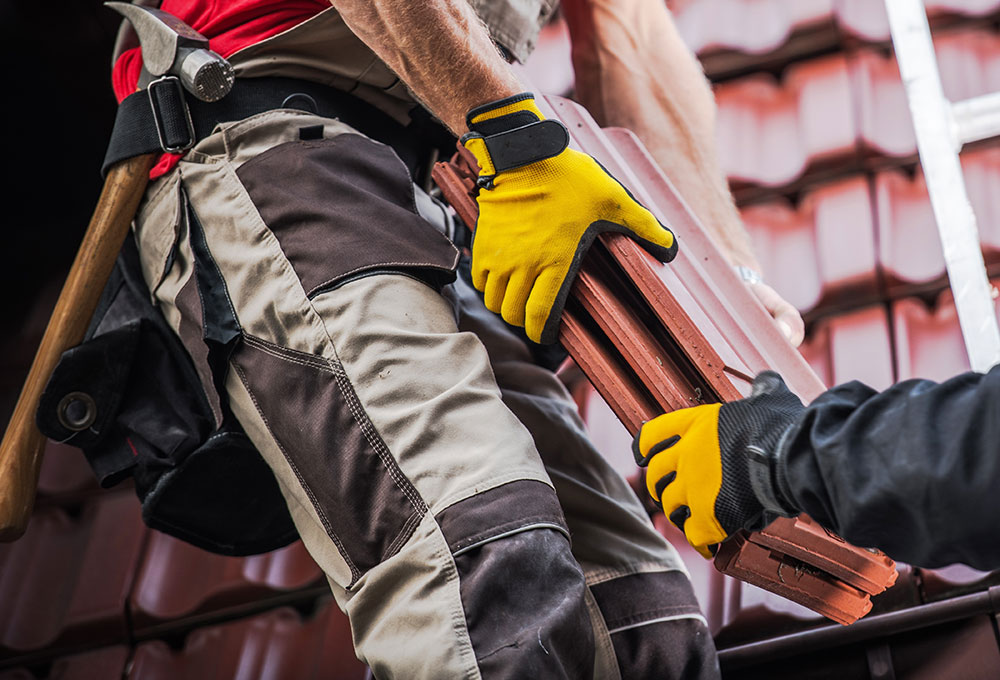 Dachdecker legt neue Dachpfannen auf ein Hausdach